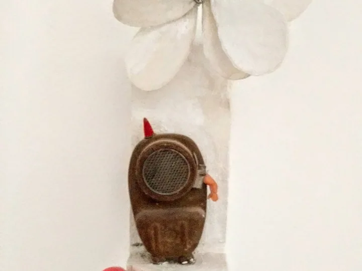 Wall-based sculptural work with a floral form and clock-like detail.